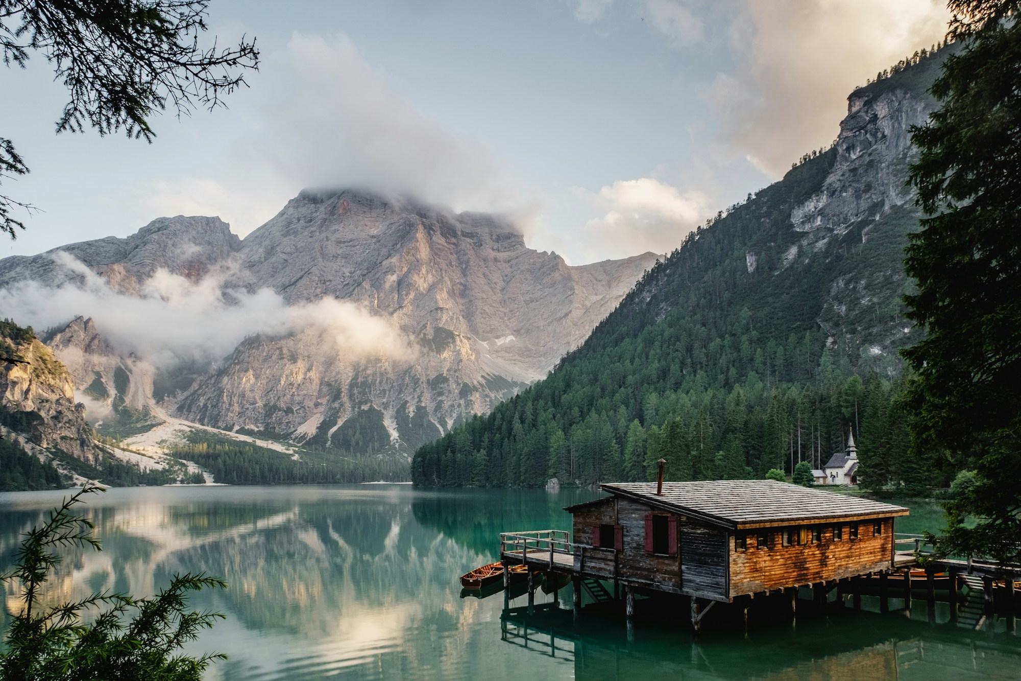 A mountain lake surrounded by forests, with a wooden boathouse at the water's edge.